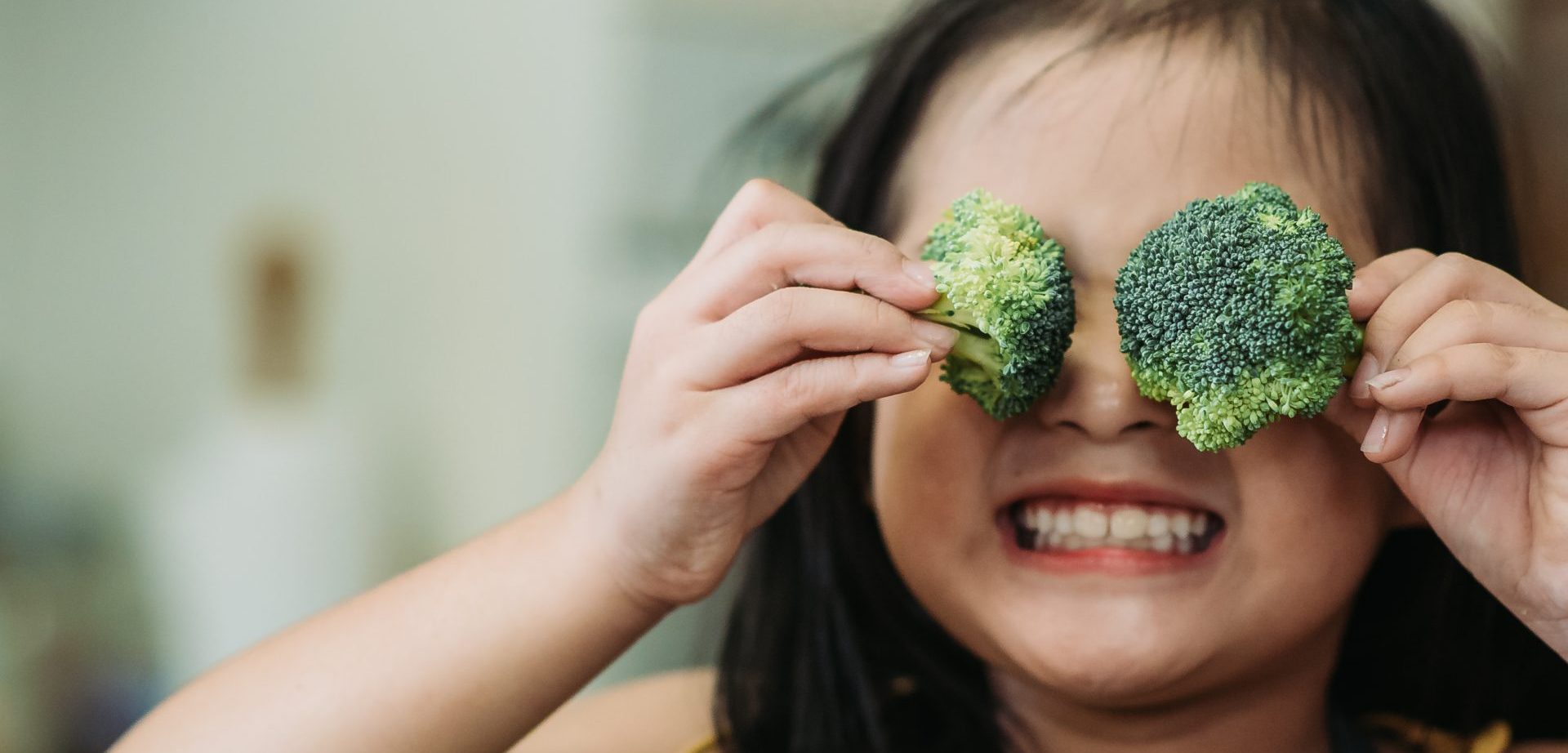 Jong meisje met 2 broccoli's voor haar ogen